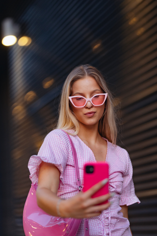 Gen Z girl in pink outfit taking selfie before going the cinema to watch movie. The young zoomer girl watched a movie addressing the topic of women, her position in the world, and body image.