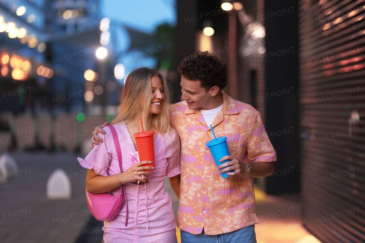 Gen Z couple in pink outfits leaving the cinema with drinks in hand. The young zoomers watched a movie addressing the topic of women, her position in the world, and body image.