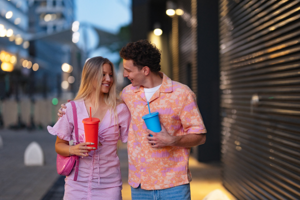 Gen Z couple in pink outfits leaving the cinema with drinks in hand. The young zoomers watched a movie addressing the topic of women, her position in the world, and body image.