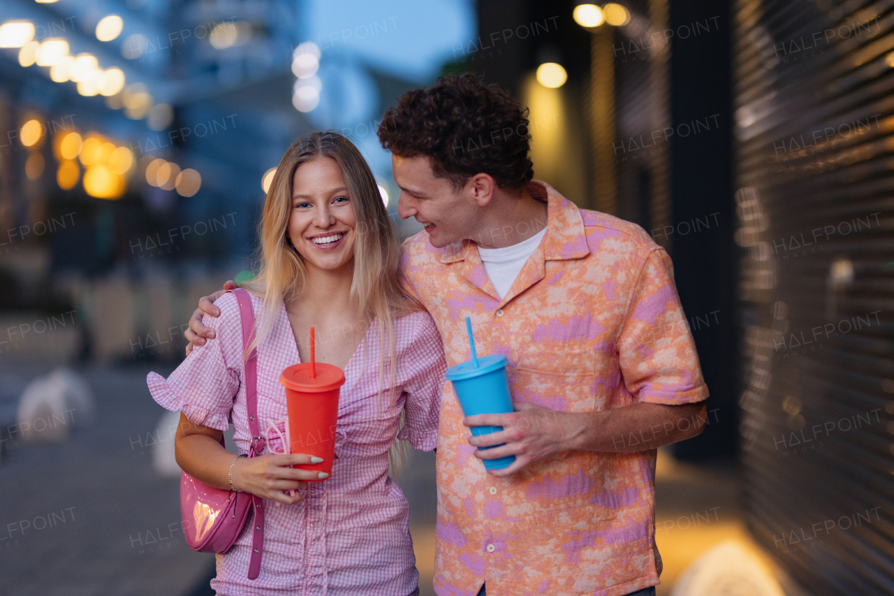 Gen Z couple in pink outfits leaving the cinema with drinks in hand. The young zoomers watched a movie addressing the topic of women, her position in the world, and body image.