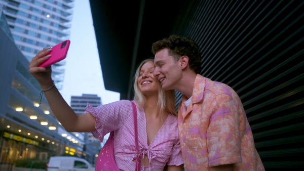 Gen Z couple in pink outfit taking selfie before going the cinema to watch movie. The young zoomer girl and boy watched a movie addressing the topic of women, her position in the world, and body image.