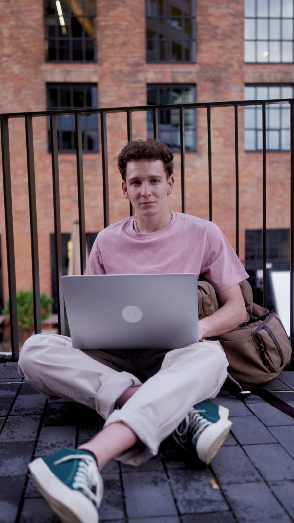 Gen Z student working on laptop after lecture on campus. Young stylish zoomer studiing outdoors. Concept of importance of education of gen Z.