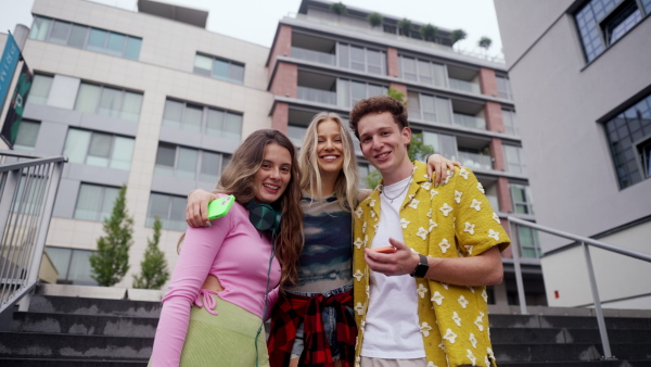 Generation z students hanging out together outdoors in the city. Young stylish zoomers are online, using smartphones, social media, taking selfies. Concept of power of friendship and social strength of gen Z. Low angle shot with copy space.