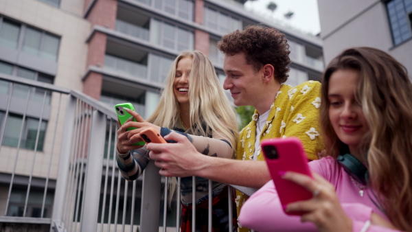 Generation z students hanging out together outdoors in the city. Young stylish zoomers are online, using smartphones, social media, taking selfies. Concept of power of friendship and social strength of gen Z.