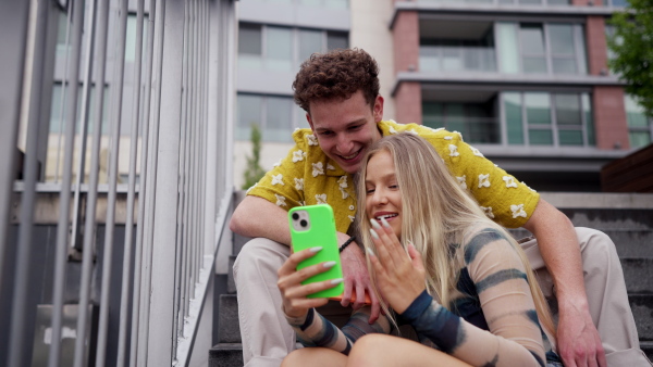 Portrait of generation z couple sitting outdoors in the city and taking selfie. Students spending free time online, watching social media content. Concept of gen Z as loneliest generation.