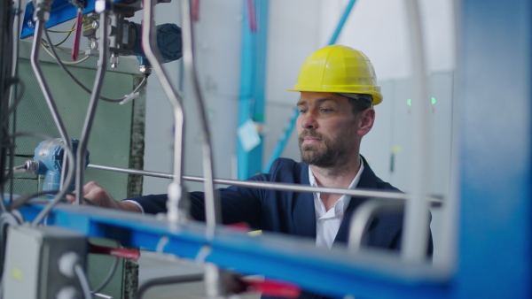 An inpector in factory with protective helmet checking processes.