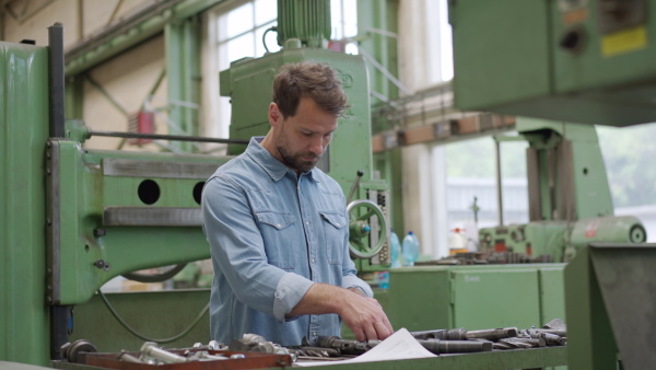 Industry worker man sorting metal drills in a warehouse.