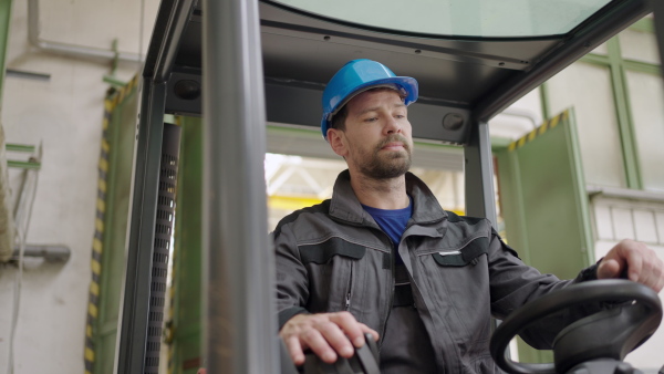 An industry worker man operating forklift in warehouse.