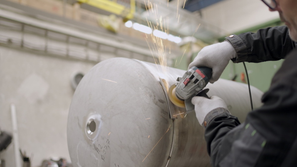 Mechanic using an electric grinder in factory, sparking, welding.