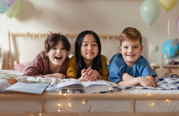 Three happy friends reading a book together in room.