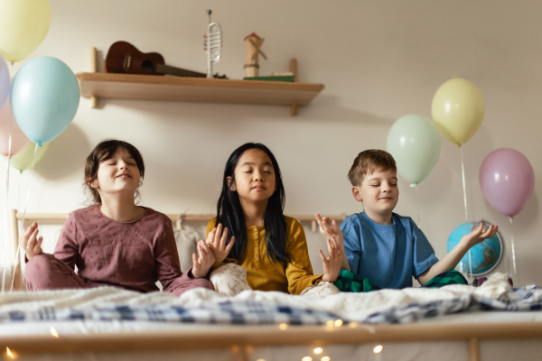 Three happy friends sitting on bed and mediating.