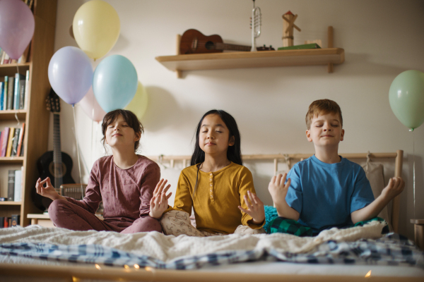 Three happy friends sitting on bed and mediating.