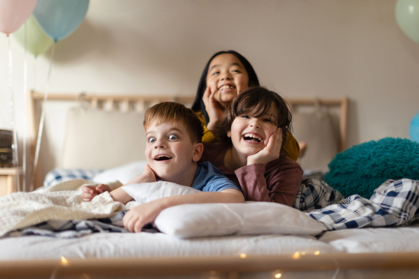 Happy children lying in the bed and having fun together.