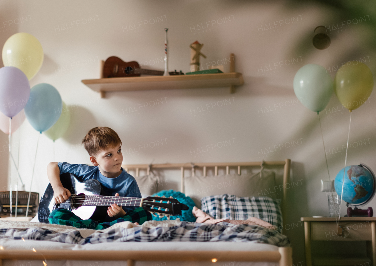 Happy boy playing on the guitar in the room.