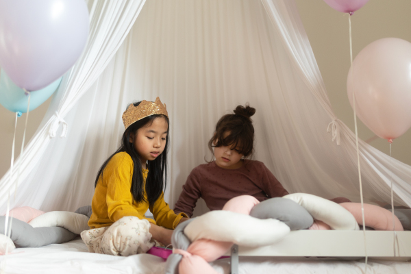 Happy girls playing princess in indoor play tent.