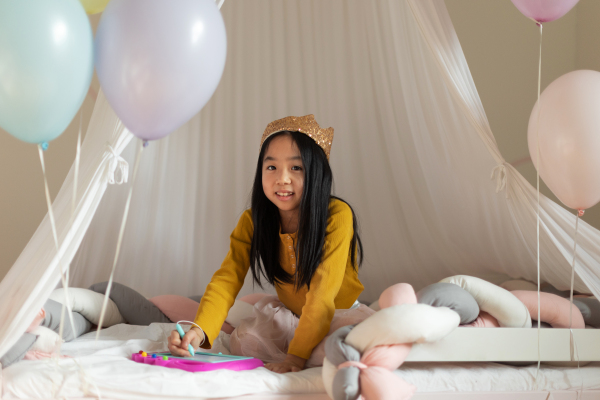 Happy girl with princess crown playing in the room.