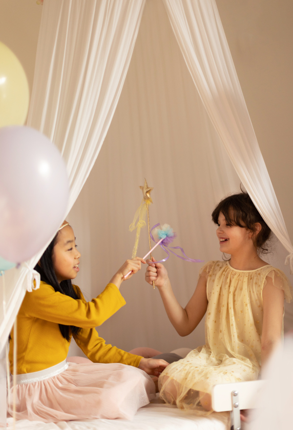 Happy girls playing on princess in room.