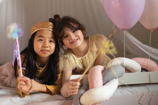 Happy girls playing on princess in room.