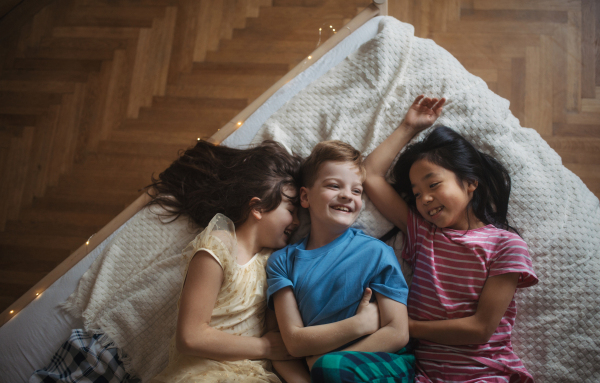 Top view of three happy friends lying in bed.