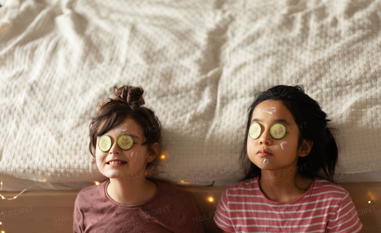 Top view of happy friends lying in bed with beauty mask on face.