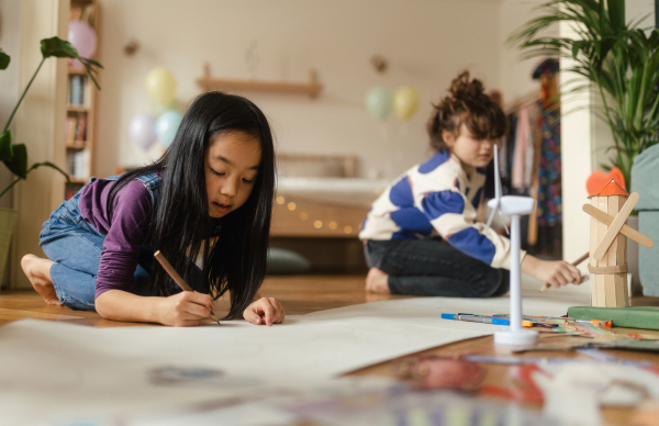 Happy friends drawing together in the room.