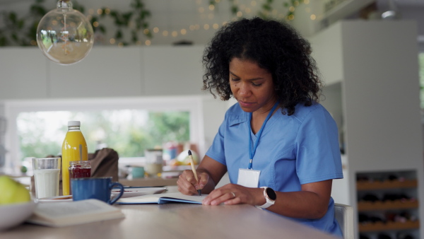 Female nurse or doctor getting ready for work in the morning, making to-do list, having breakfast, drinking glass of milk, before leaving for the work. Work-life balance for healthcare worker.