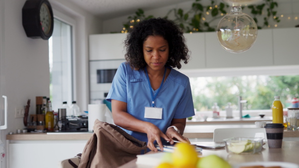 Female nurse or doctor getting ready for work, packing backpack with lunchbox, snacks and coffee, leaving house in scrubs. Work-life balance of healthcare worker as parent and partner.