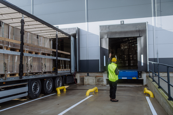 Warehouse receivers unloading of the truck in front of warehouse, checking delivered items. Unloading cargo.