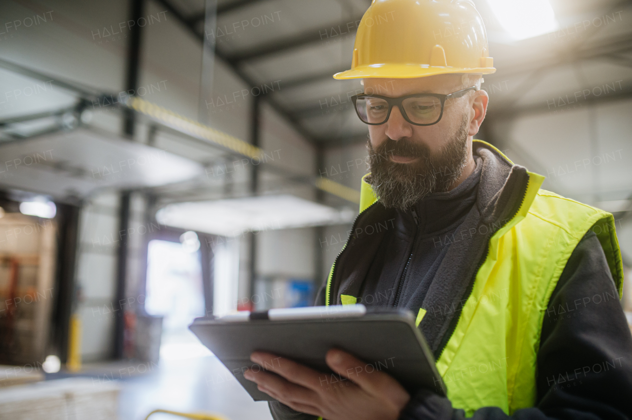 Warehouse receiver, clark standing by delivered cargo, holding tablet, looking at cargo details, checking delivered items, goods against order.