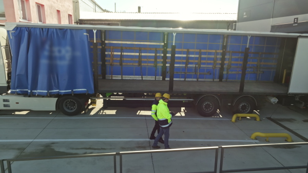 A side view of warehouse receivers unloading of the truck in front of warehouse.