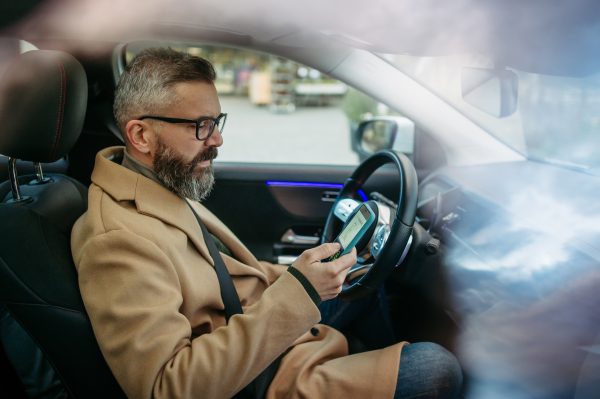 Close up of man using electric vehicle charging app, checking battery status, level on smart phone. Charging apps for monitoring electricity usage, locating charging stations.