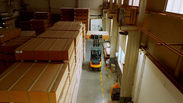 A top view of warehouse worker driving forklift. Warehouse worker preparing products for shipmennt, delivery, checking stock in warehouse.