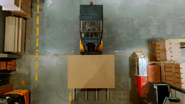 A top view of warehouse worker driving forklift. Warehouse worker preparing products for shipmennt, delivery, checking stock in warehouse.