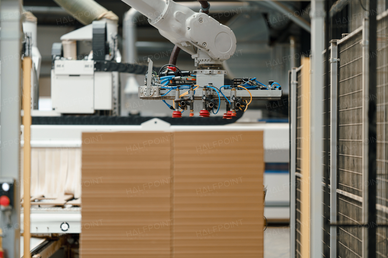 Close up of robotic arm in modern industrial factory, production of wooden furniture. Big modern furniture manufacturing facility with robotics and automation.