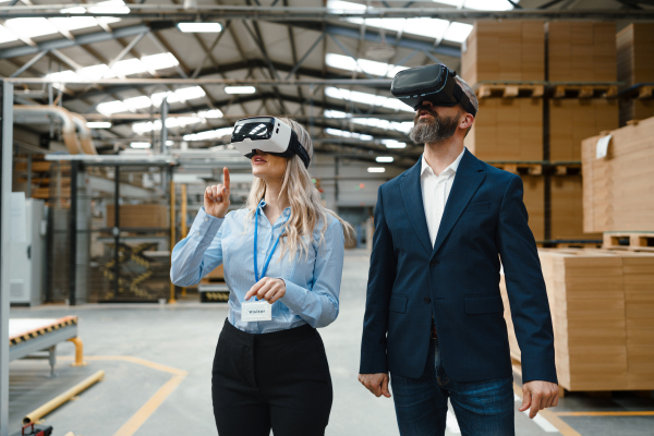 Engineers talking project using VR, in modern industrial factory. Virtual reality and technology in manufacturing industry, Smart glasses AR, guiding female and male managers through process and planing.