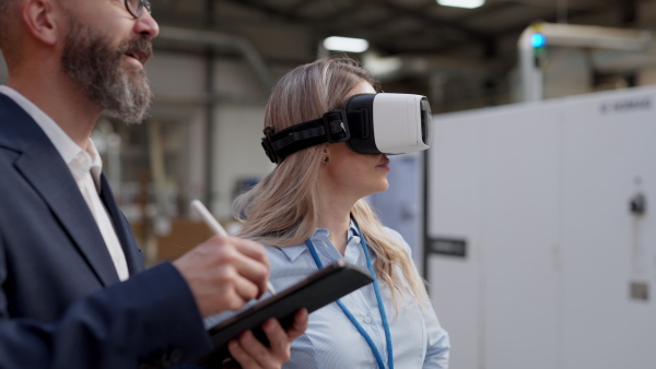 Warehouse managers talking logistics using VR, controlling stock levels, discussing shipping process. Virtual reality in inventory management. Smart glasses guiding female manager through warehouse, recording tracking data and quicken picking process.