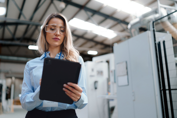 Portrait of female manager standing in modern industrial factory. Manufacturing facility with robotics and automation. Female leader, CEO in heavy industry, manufactury.