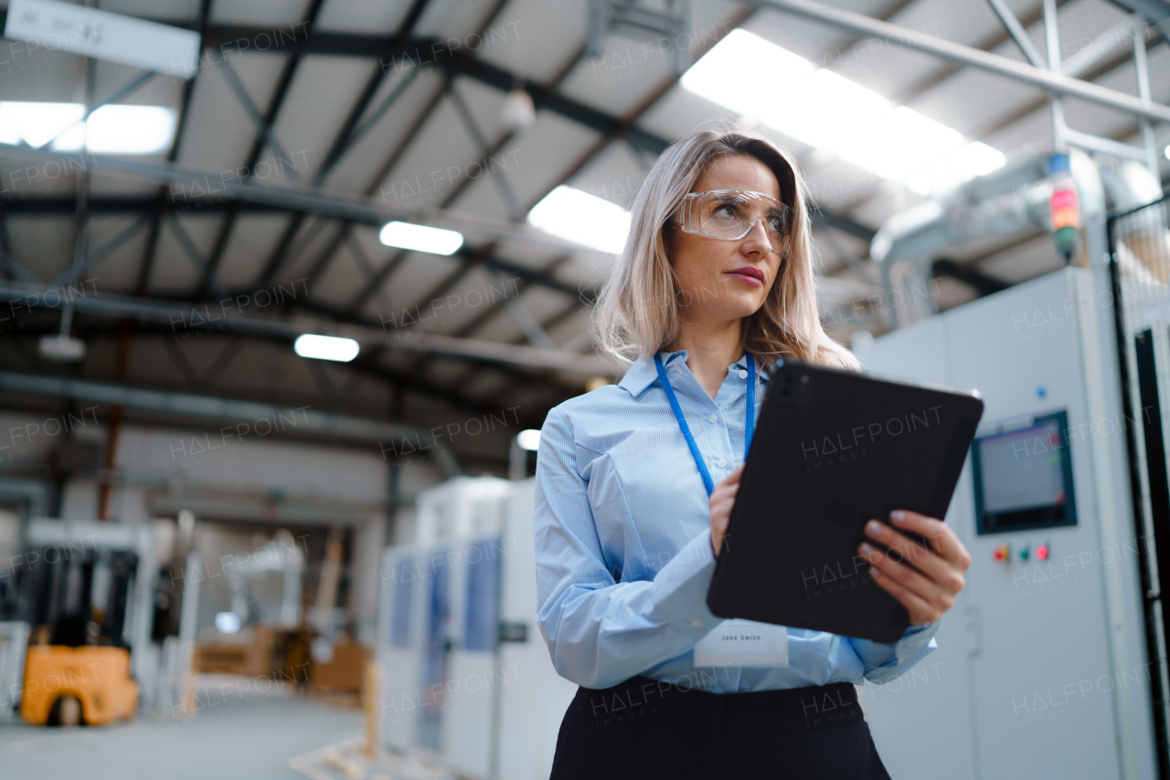 Portrait of female manager standing in modern industrial factory. Manufacturing facility with robotics and automation. Female leader, CEO in heavy industry, manufactury.