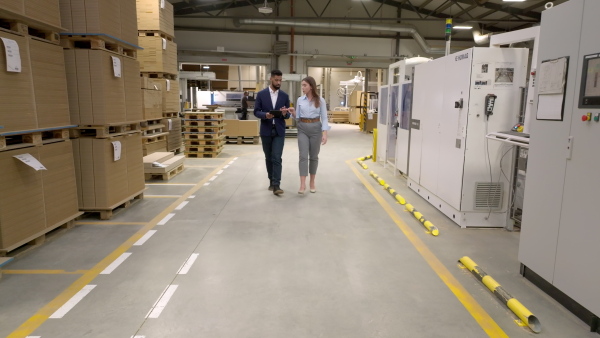 Female warehouse manager talking with logistics employee in warehouse, planning transport of products, goods, talking shipping process. Storing products and materials in warehouse.