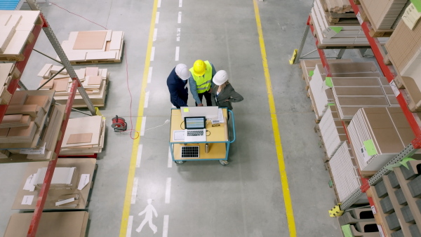 Top view of female engineer, foreman consulting with director in modern industrial factory, talking about new production project, investment. Team management in manufacturing facility.