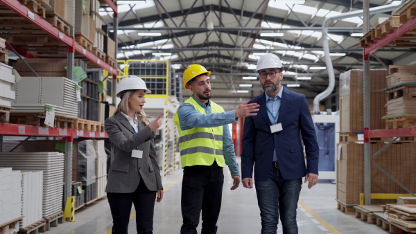 Engineers consulting with director in modern industrial factory, talking about new production project, investment. Team management in manufacturing facility.