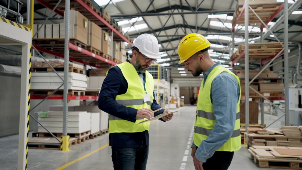 Engineers shaking hands with project manager in modern industrial factory, talking about new production project, investment. Team management in manufacturing facility.