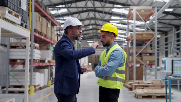 Supervisor, manager scolding employee in modern industry factory. Worker making mistake. Production manger is angry, dissatisfied for worker's poor quality work or safety viaolations.