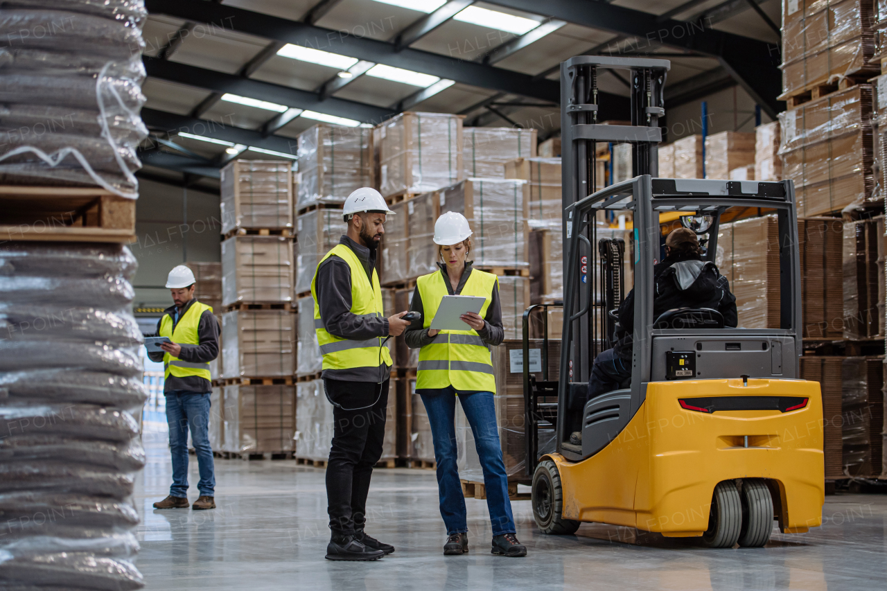 Warehouse workers reading product order, order picking. Warehouse manager checking delivery, stock in warehouse, inspecting products for shipment, talking with colleague.