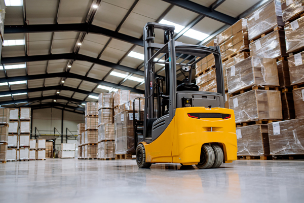 Forklift in warehouse in the middle of stored goods. Forklift driver preparing products for shipmennt, delivery, checking stock in the warehouse.