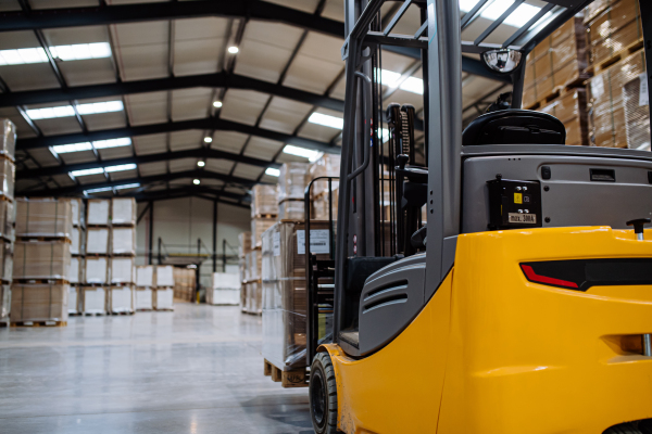 Forklift in warehouse in the middle of stored goods. Forklift driver preparing products for shipmennt, delivery, checking stock in the warehouse.