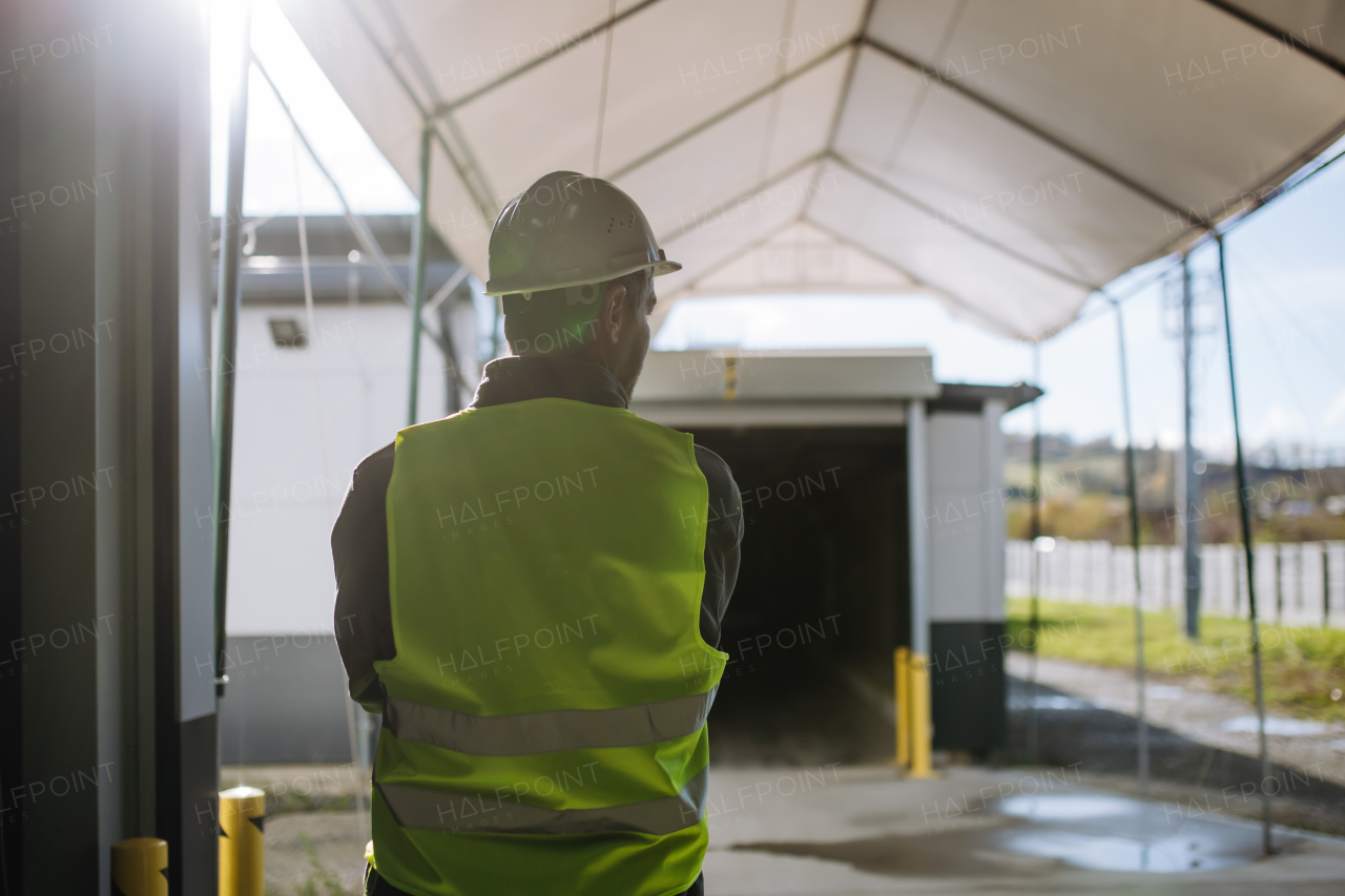 Rear view of a warehouse worker waiting on loading dock for loading vehicle, delivery truck.