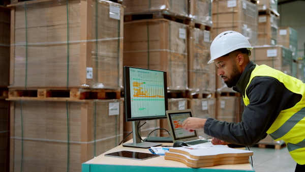 Video of warehouseman checking delivery, stock in warehouse on company pc, computer. Warehouse manager using warehouse management software, app.