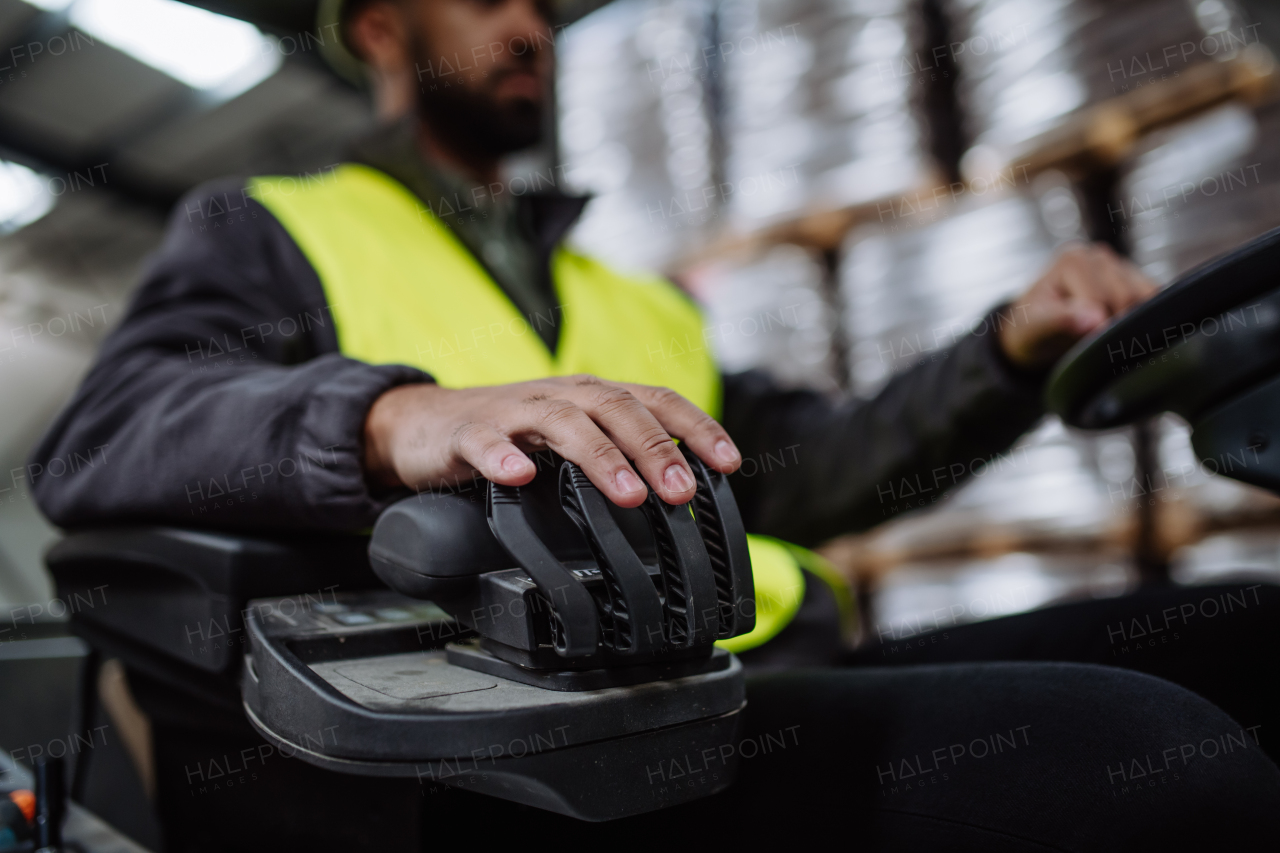 Close up of hand of multiracial warehouse worker driving forklift. Warehouse worker preparing products for shipmennt, delivery, checking stock in warehouse.