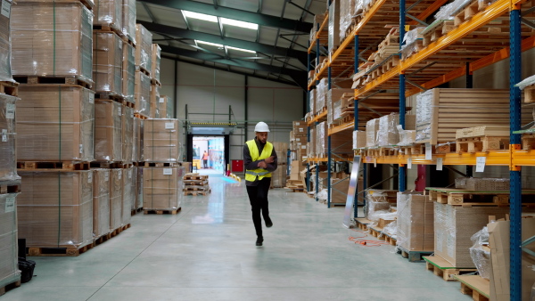 Warehouseman with tablet helmet dancing in the middle of the warehouse. Warehouse working having fun at work.